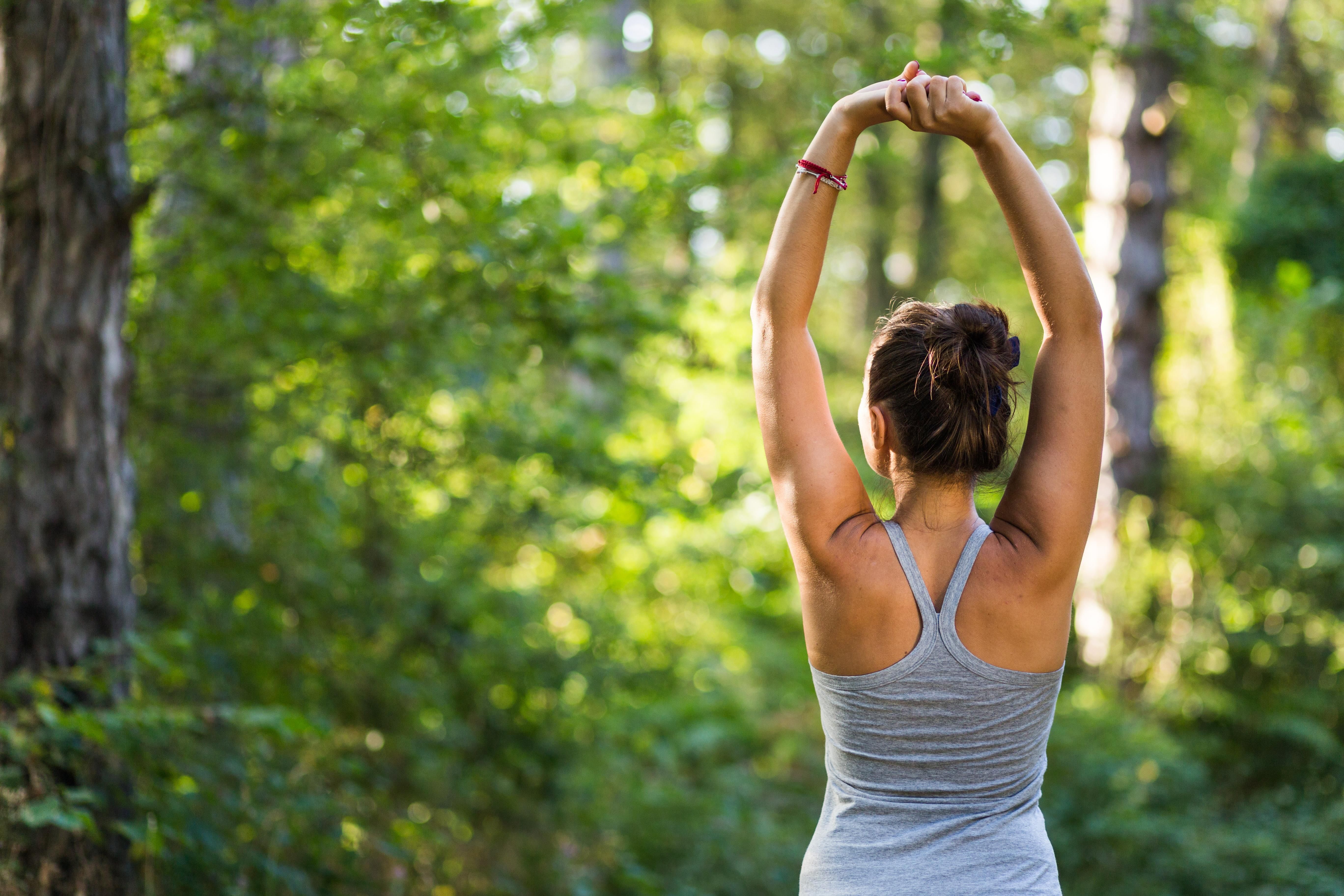 Frau führt Atemübungen im Wald durch.