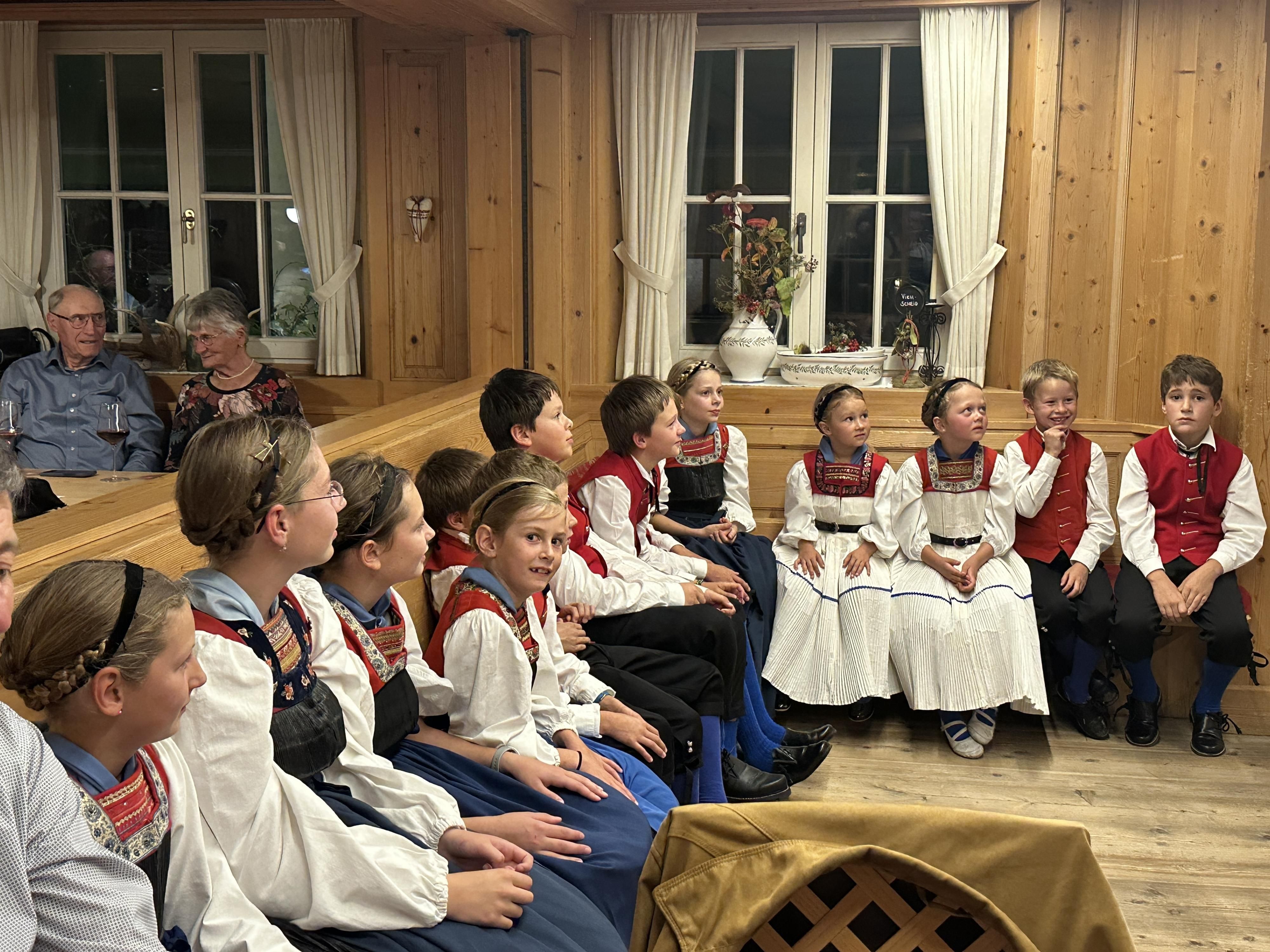 Mann sieht einige mitglieder des Trachtenverreins auf Stühlen in einer Runde sitzen.