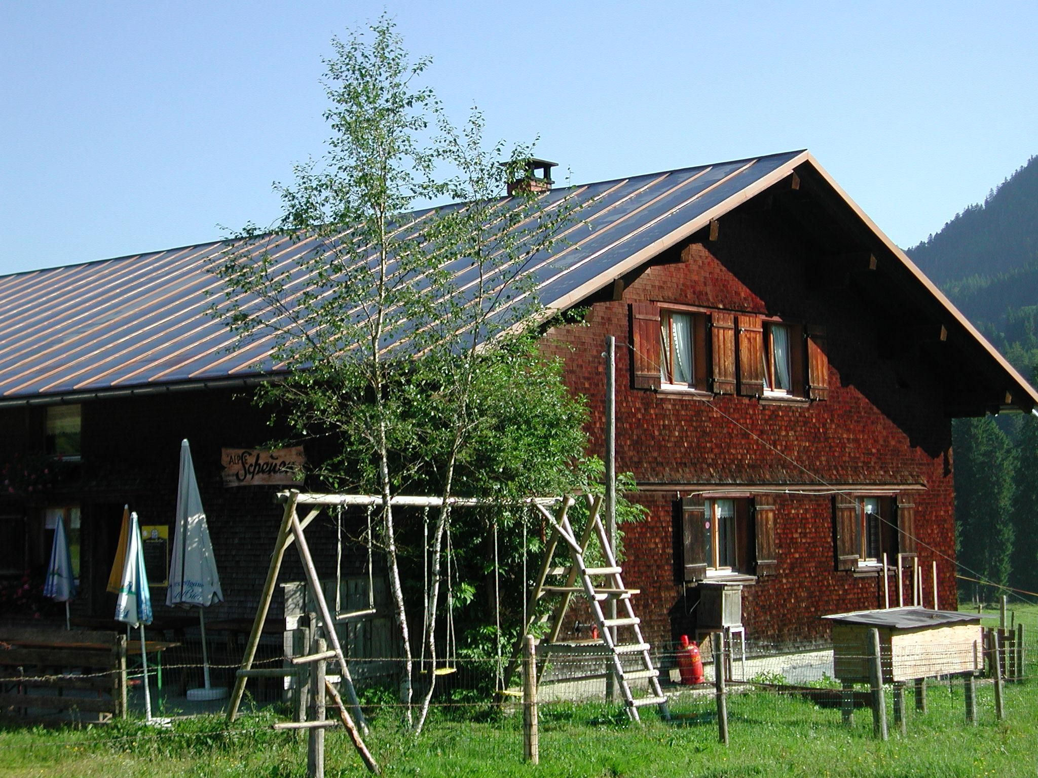 Alpe Scheuen in Balderschwang, Berghütte mit Holzschindeln, Spielplatz und Sonnenschirmen.