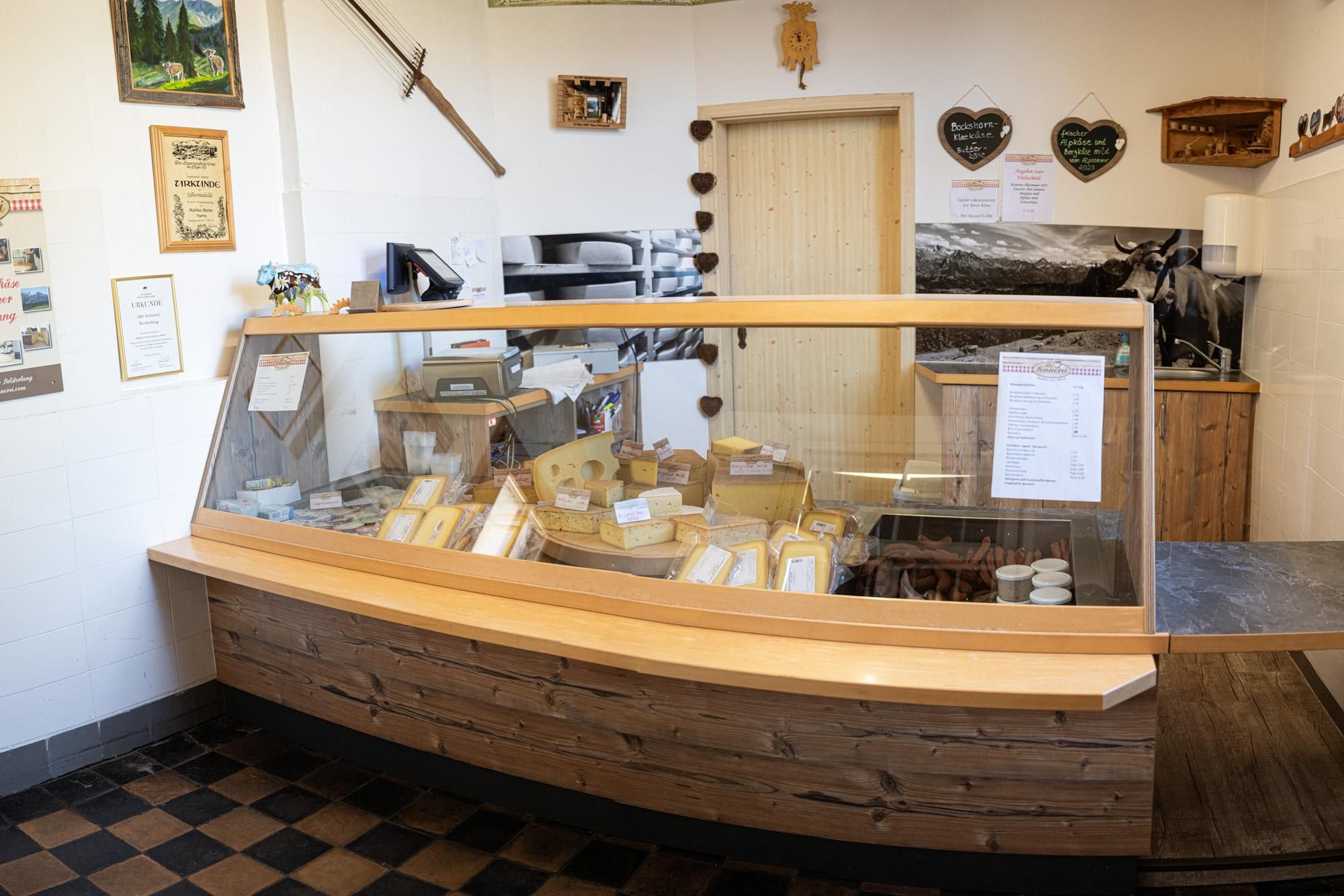 Eine Käsetheke in der Alten Sennerei Bolsterlang zeigt verschiedene Käsesorten in einer Glasvitrine.