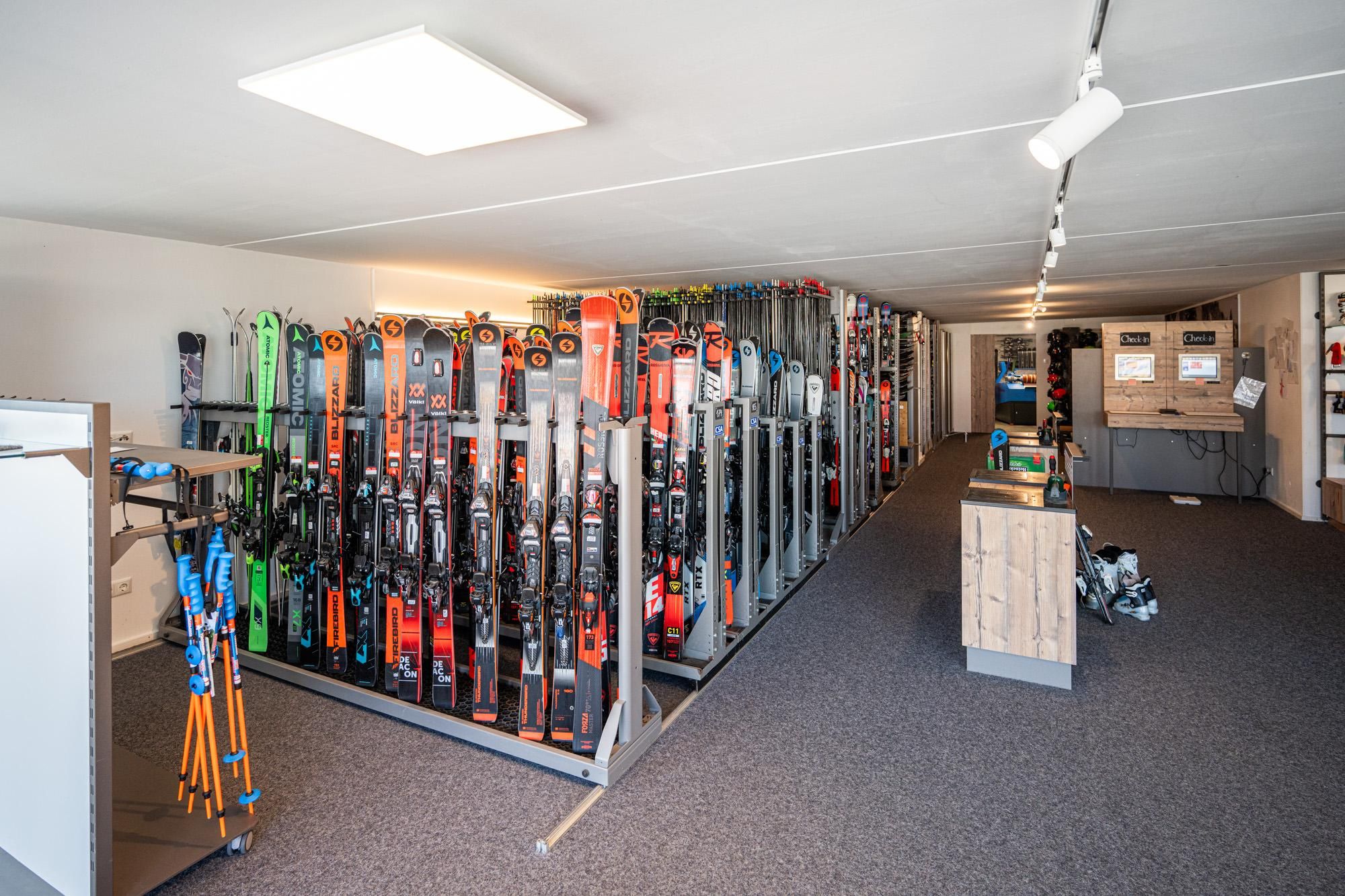 Innenraum der Ski- und Snowboardschule in Bolsterlang. Zahlreiche Skier und Skistöcke in Regalen.