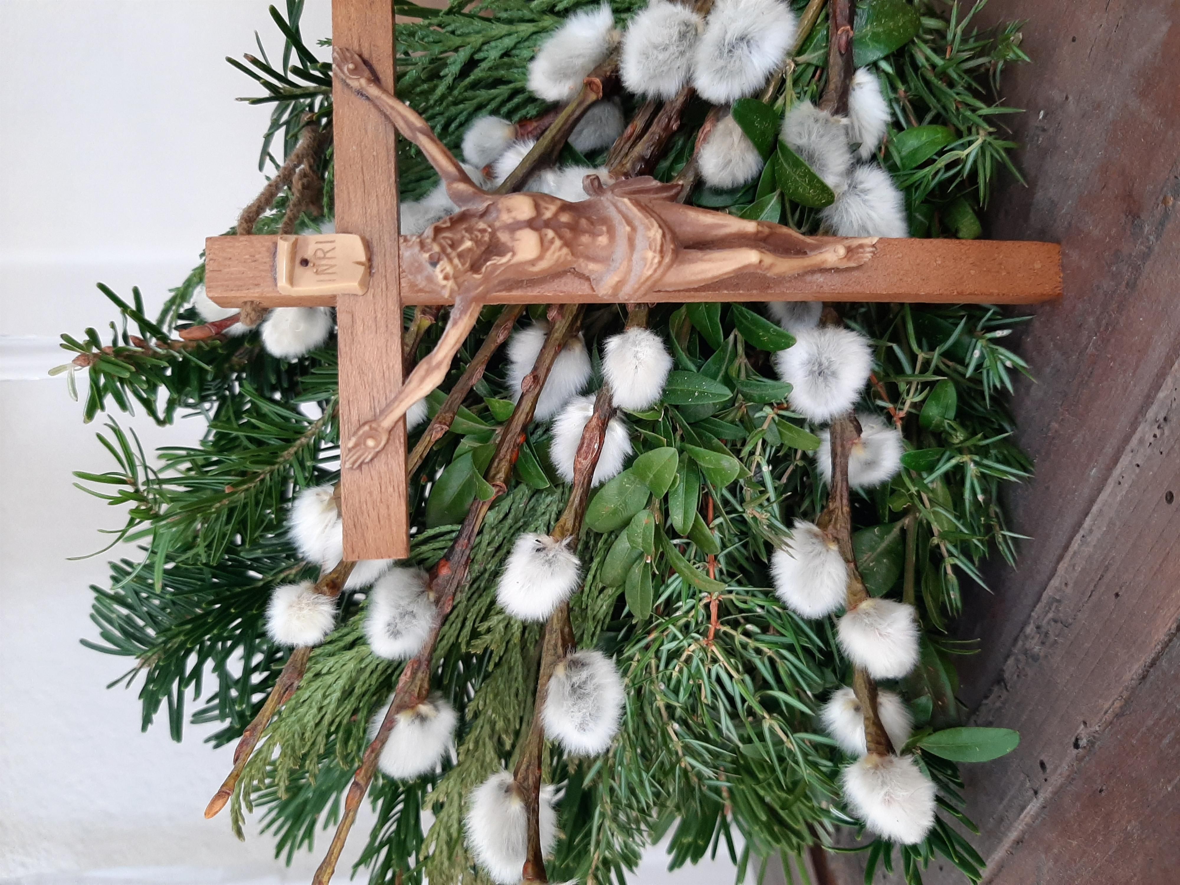 Ein Palmsträusschen wie es in Fischen im Allgäu gebunden wird mit Weissdaas, Palmkätzchen, Stechpalmen und Buchs hinter dem Kreuz.