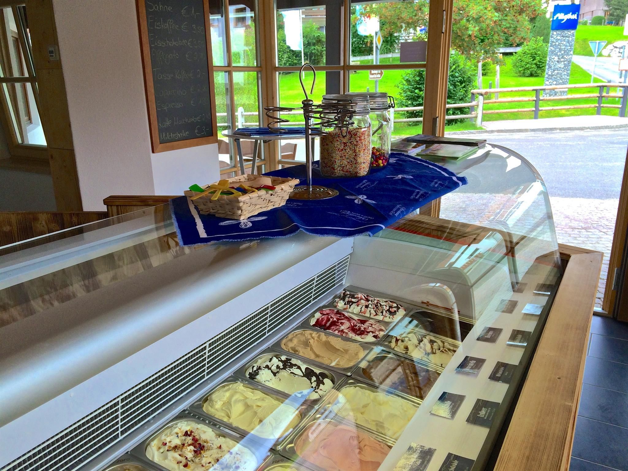 Eistheke im Eisladen Ofterschwang. Verschiedene Eissorten in Behältern unter einer Glasabdeckung.