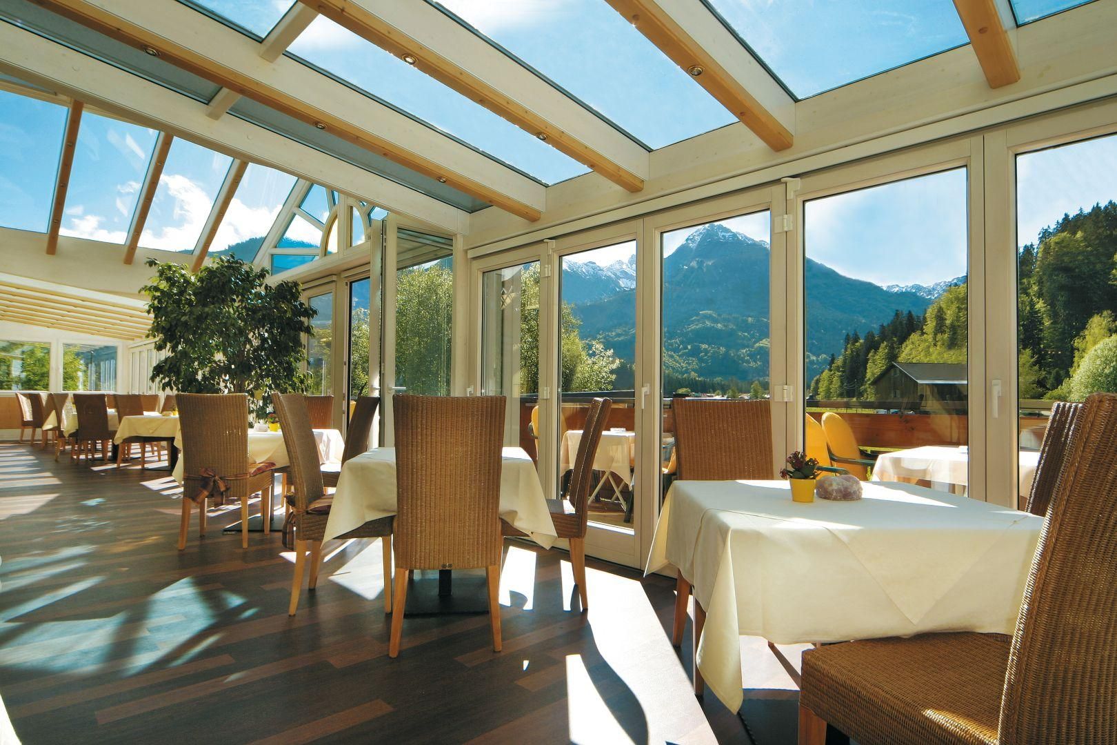Der Wintergarten im Hotel Sonnenbichl, Korbstühle und weiß gedeckte Tische.