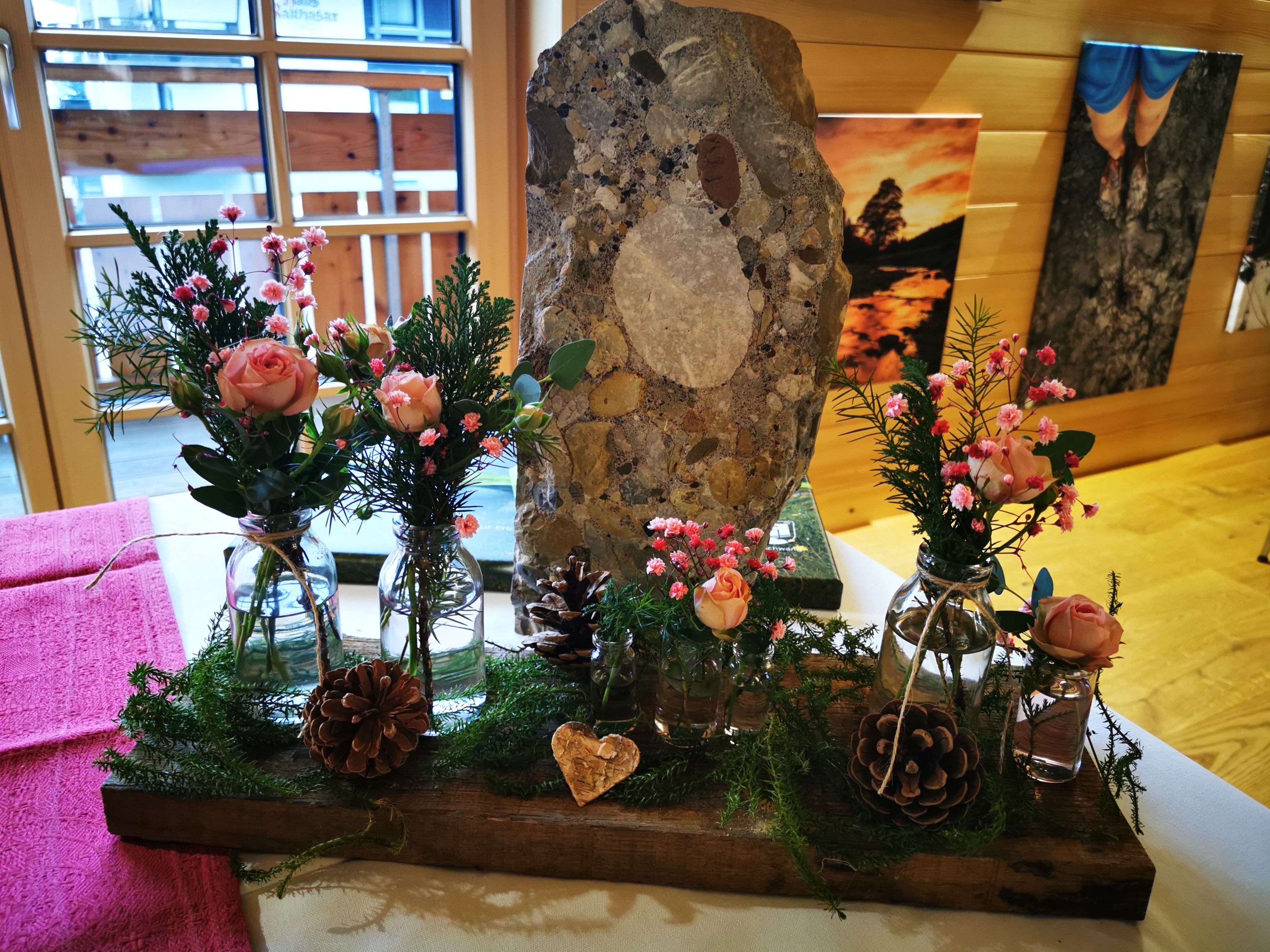 Romantisches Blumengesteck auf dem Trautisch im Dorfhaus Balderschwang mit Rosen und Tannengrün. Nagelfluhstein als Dekoration mit ins Gesteck integriert.