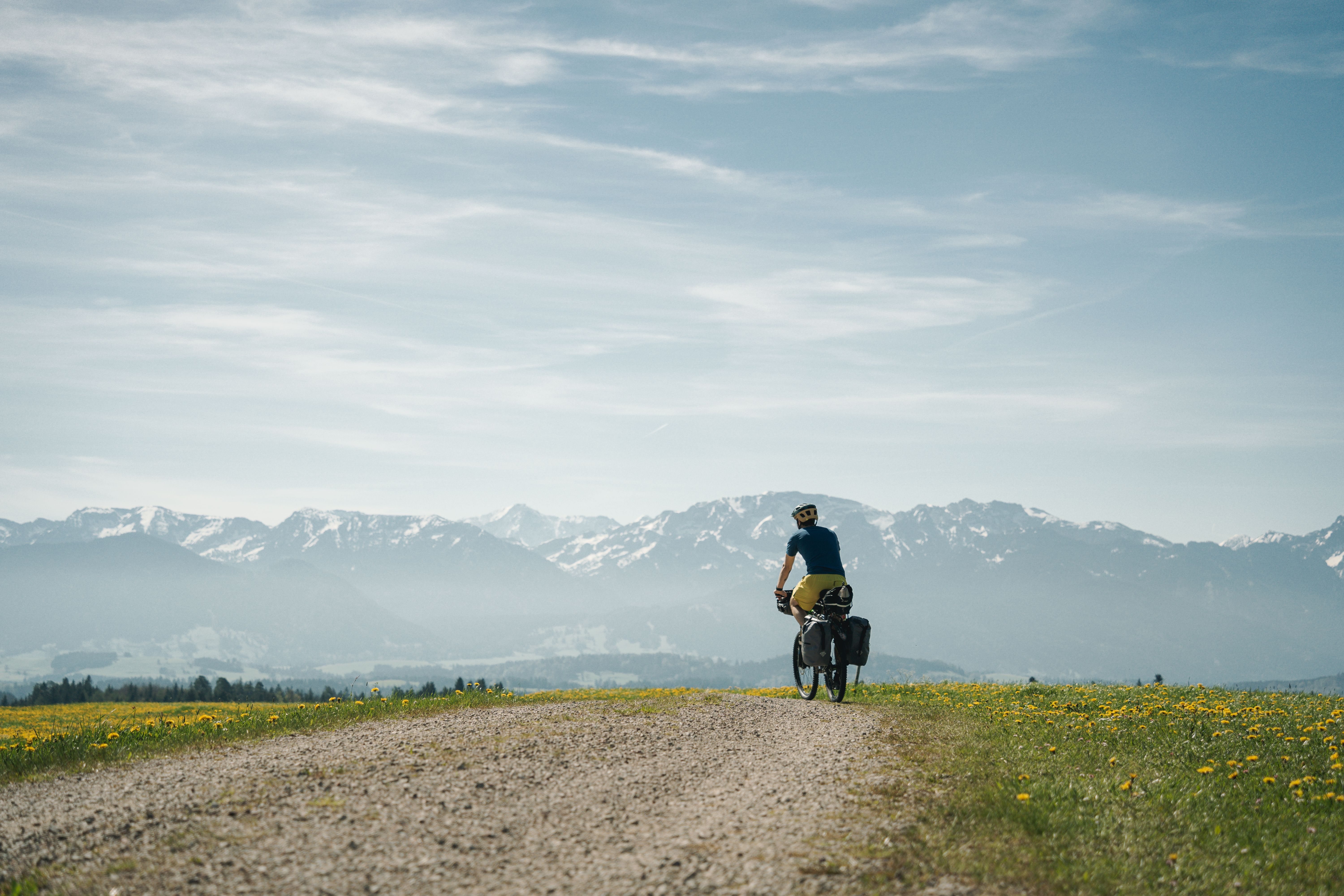 Fahrradfahrer auf Schotterweg mit Bergpanorama im Hintergrund