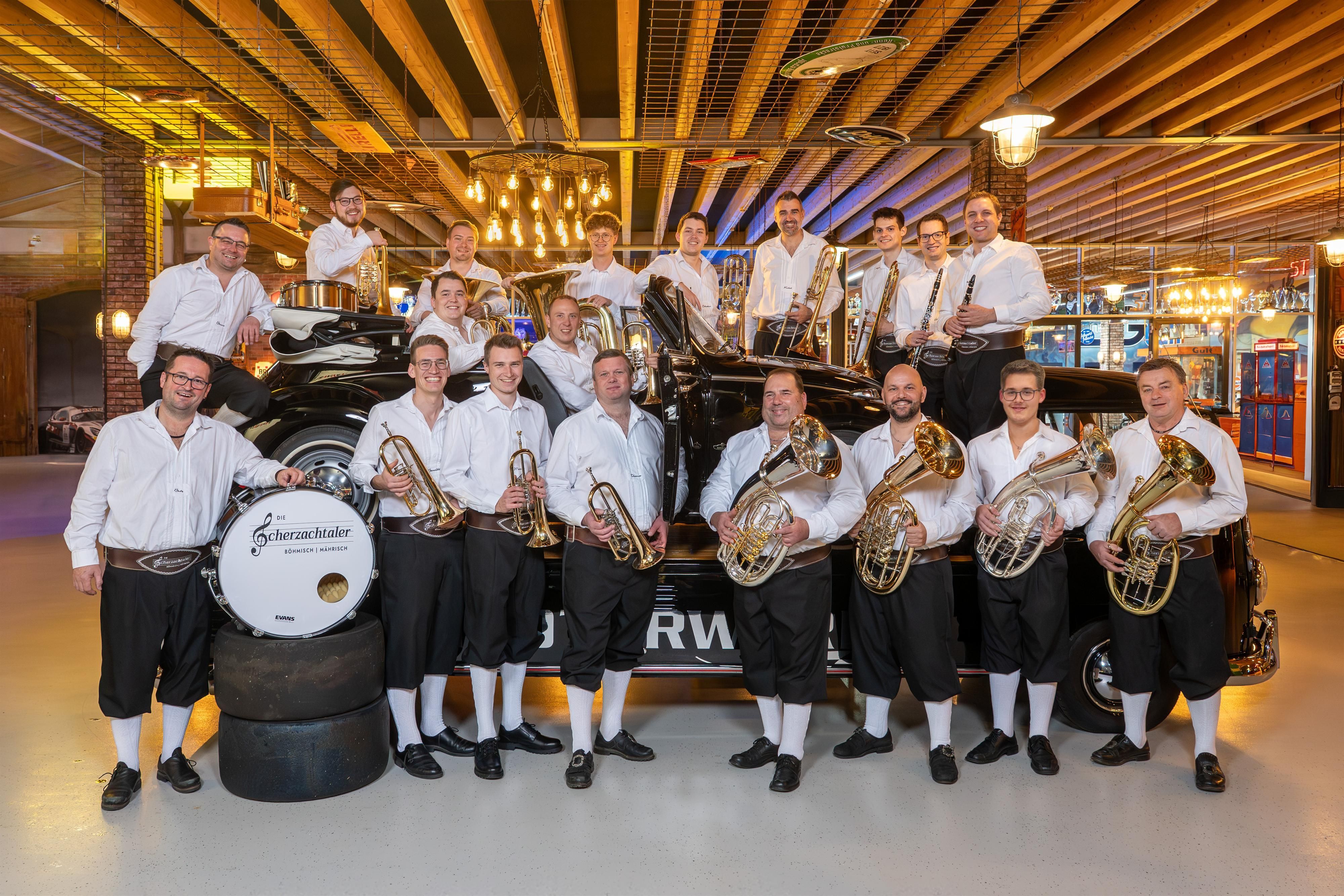 Das Gruppenbild der Scherzachtaler bei dem alle Musiker im weißen Hemd mit den Instrumenten im Arm positioniert sind.