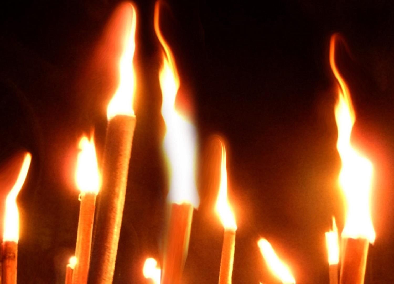 Nahaufnahme von mehreren hell brennenden Fackeln vor einem dunklen Hintergrund.
