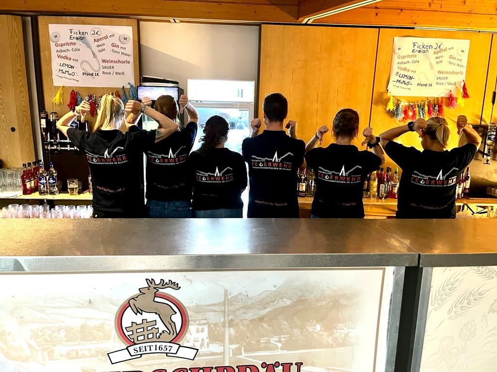 Die Bar in einem Getränkewagen, es gibt Aperol, Wein und Schnaps, sechs Personen von hinten.