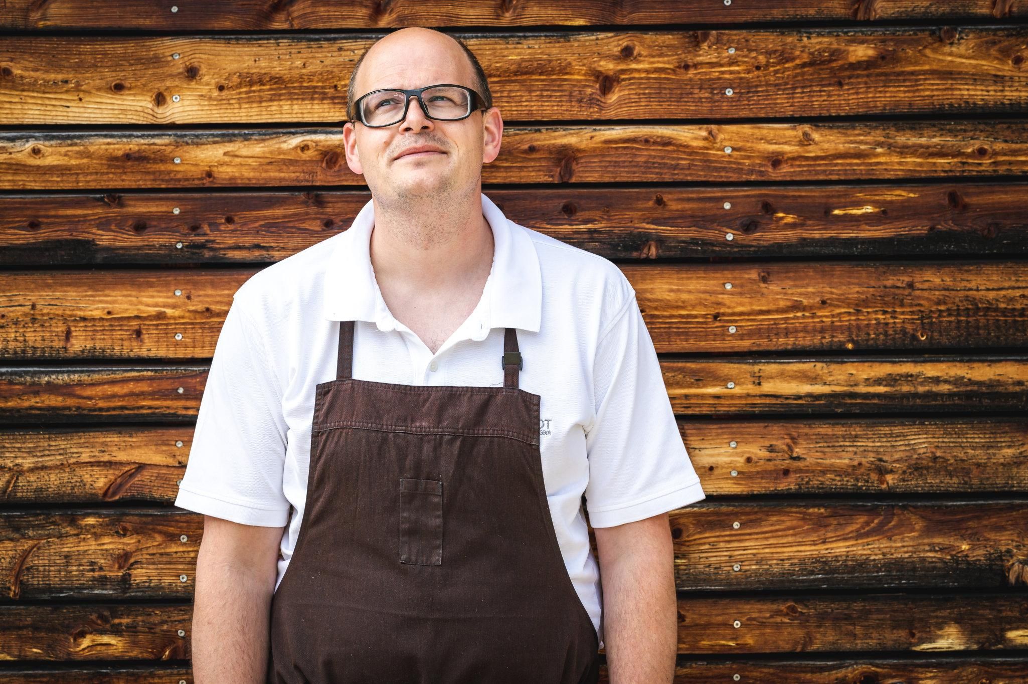 Bäcker mit brauner Schürze und weißem Poloshirt.