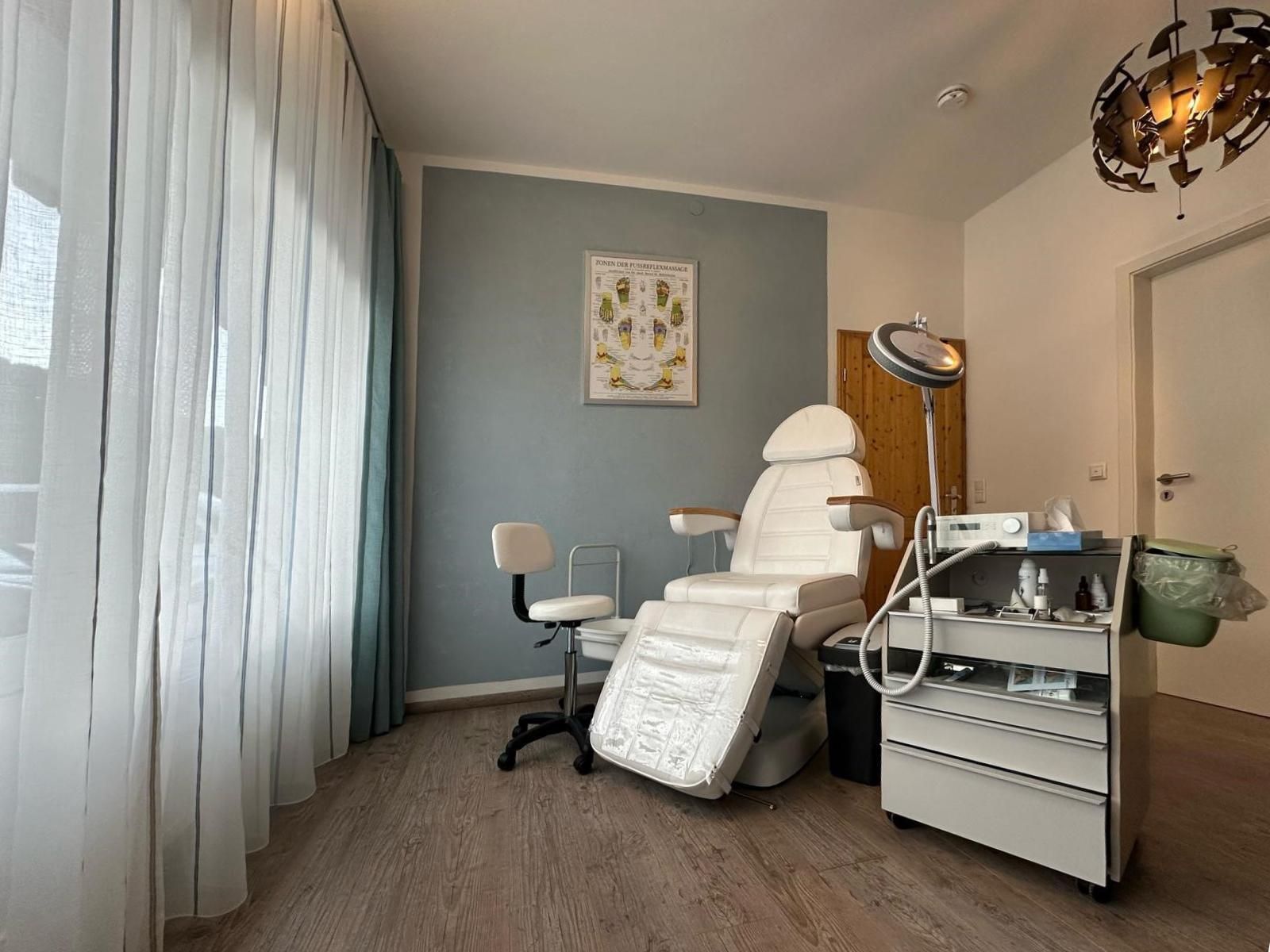 <p>Heller und freundlicher Behandlungsraumin der Fuss Oase in Bolsterlang. In der Mitte steht ein Behandlungsstuhl.</p>
