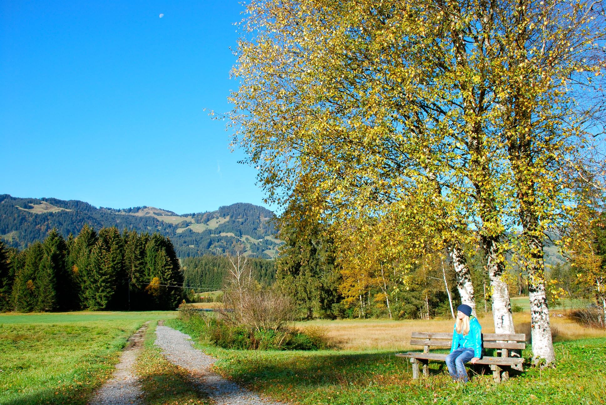 Wanderer auf einer Bank in herbstlicher Landschaft am Tiefenberger Moos