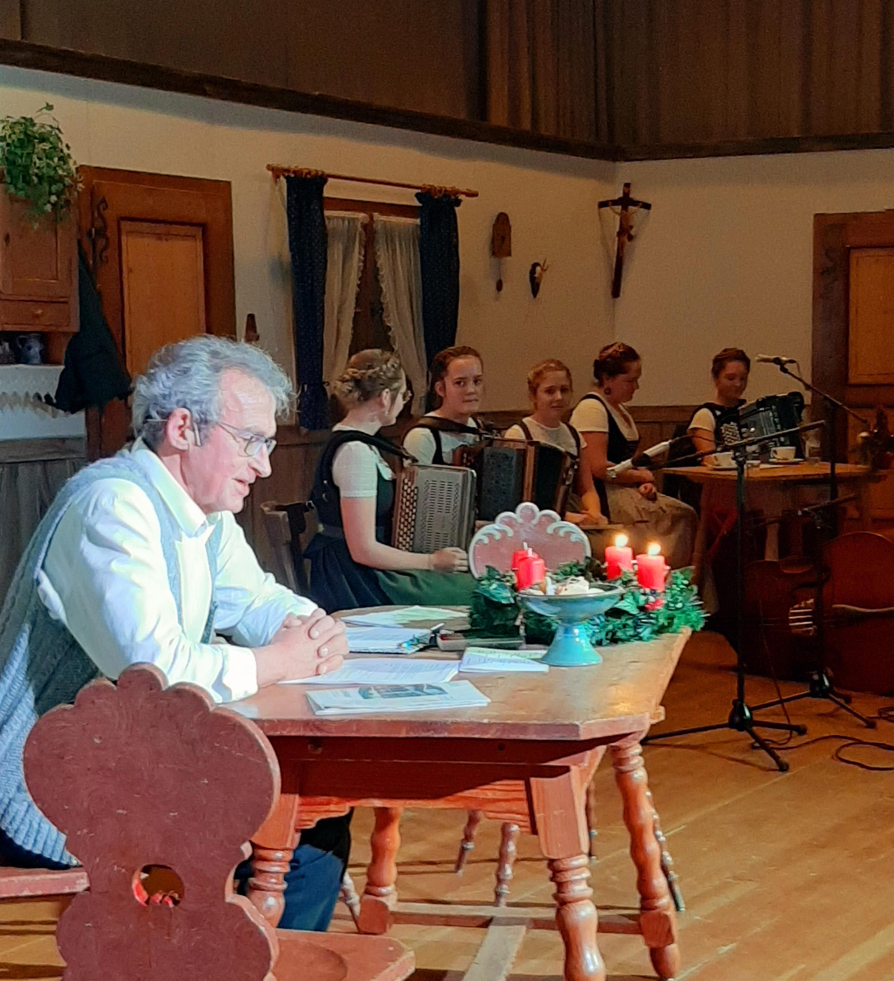 weihnachtliche Stimmung am Holztisch mit dem Sprecher Helmut Rothmayr auf der Bühne im Kurhaus Fiskina in Fischen