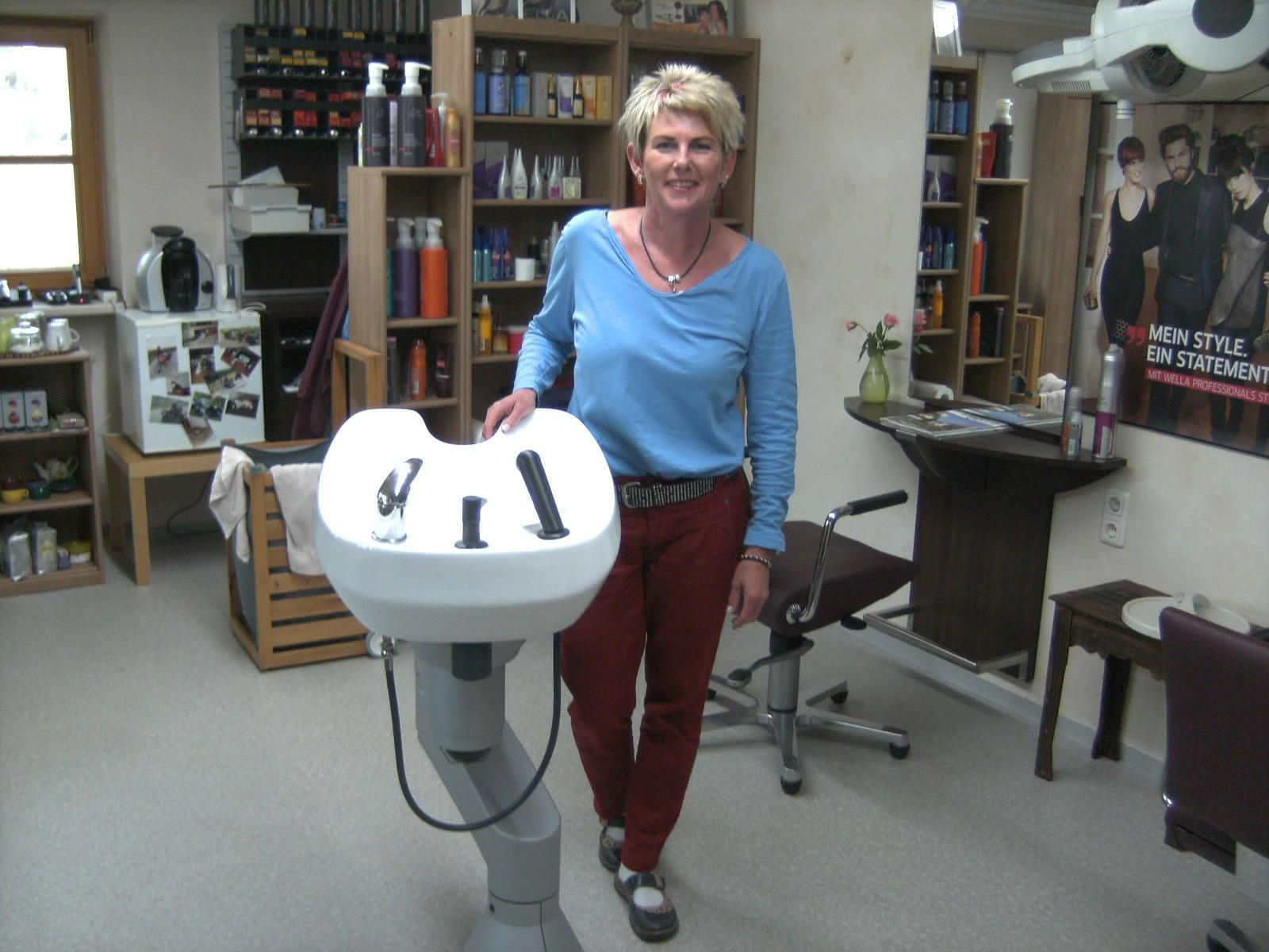 Heller, freundlicher Friseursalon Haarmonie. Mehrere Frisierplätze mit Spiegeln und Stühlen. Regale mit Pflegeprodukten.