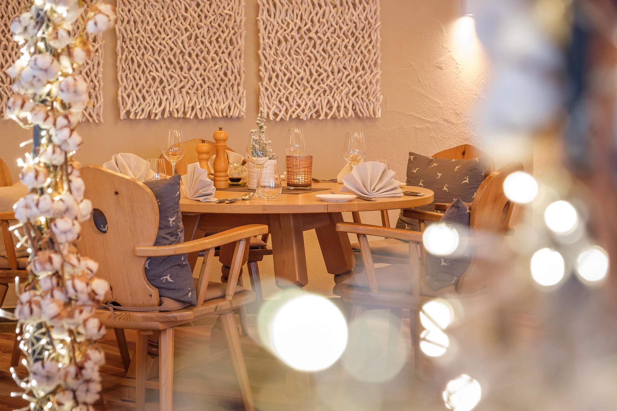 Ein weihnachtlich geschmückter Raum mit Lichterketten, im Hintergrund ein ebenso weihnachtlicher gedeckter Tisch.