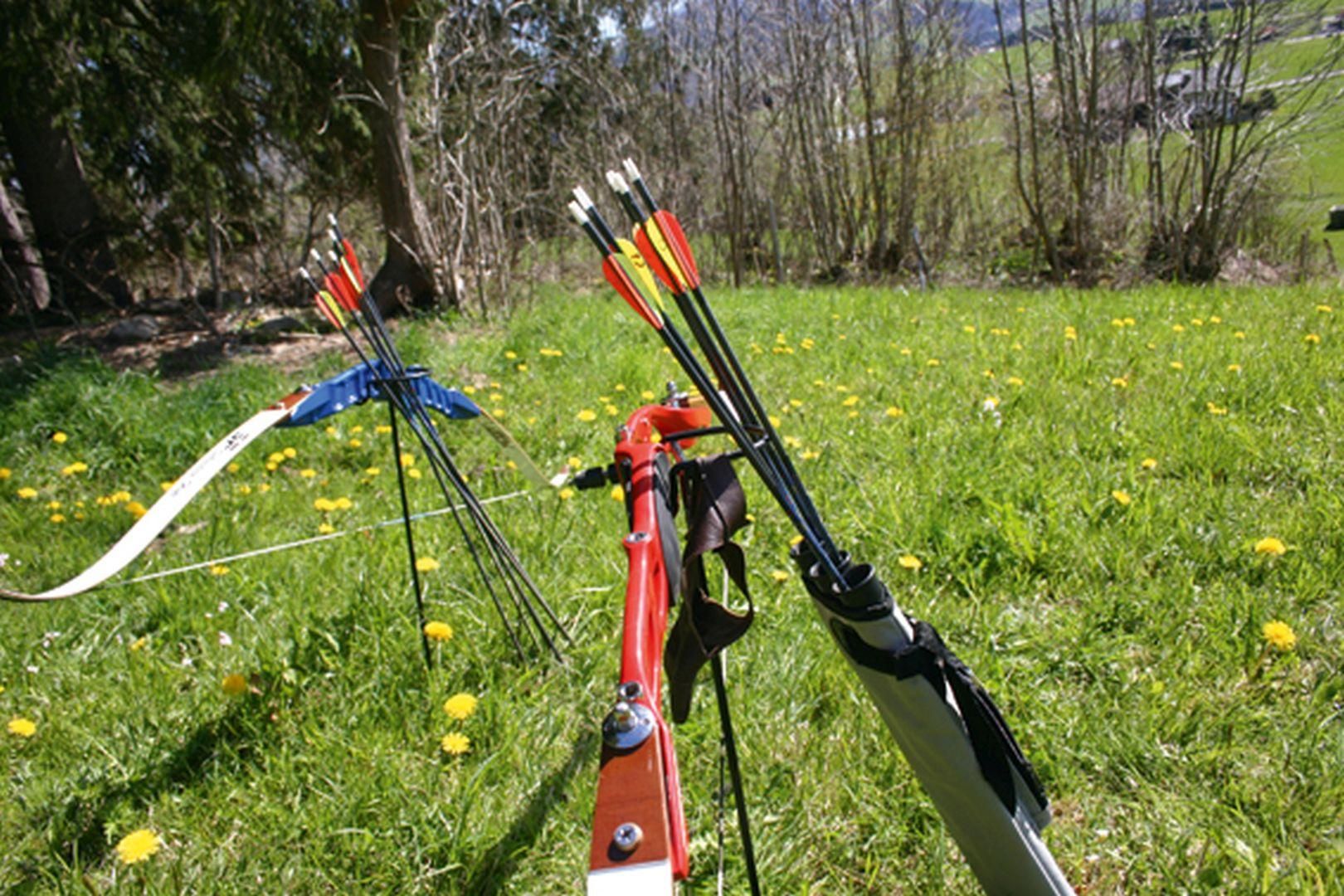 Zwei gespannte Bögen und Köcher mit Pfeilen auf einer grünen Wiese