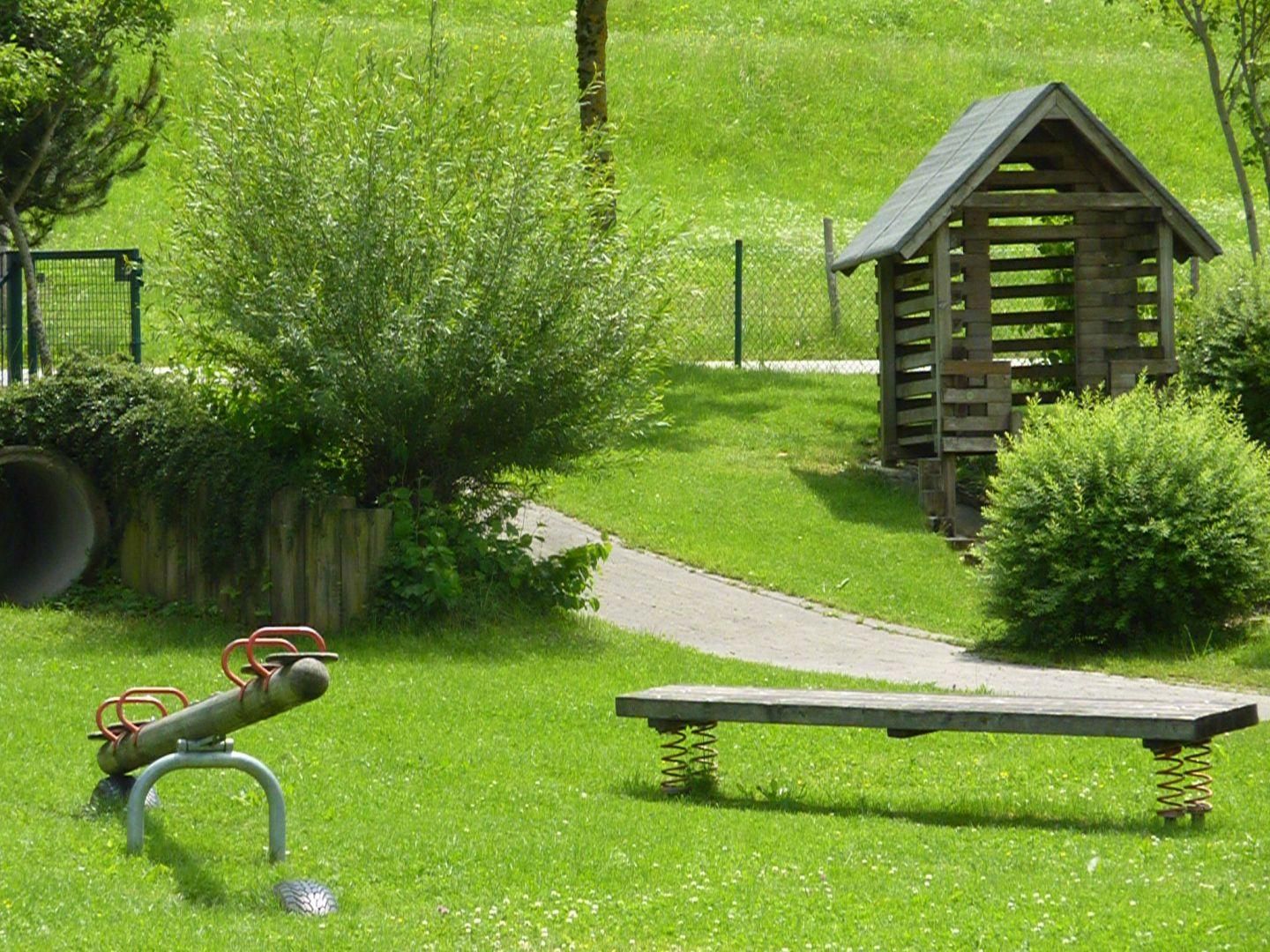 Spielplatz in Bolsterlang. Schaukel, Bank, Spielhaus und Grünfläche.