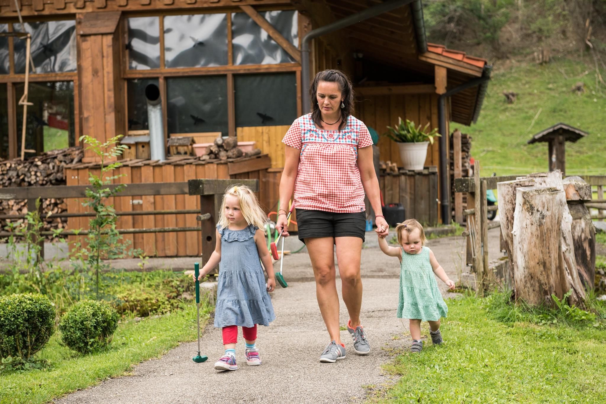 Eine Frau geht mit zwei kleinen Mädchen auf einem Kiesweg.