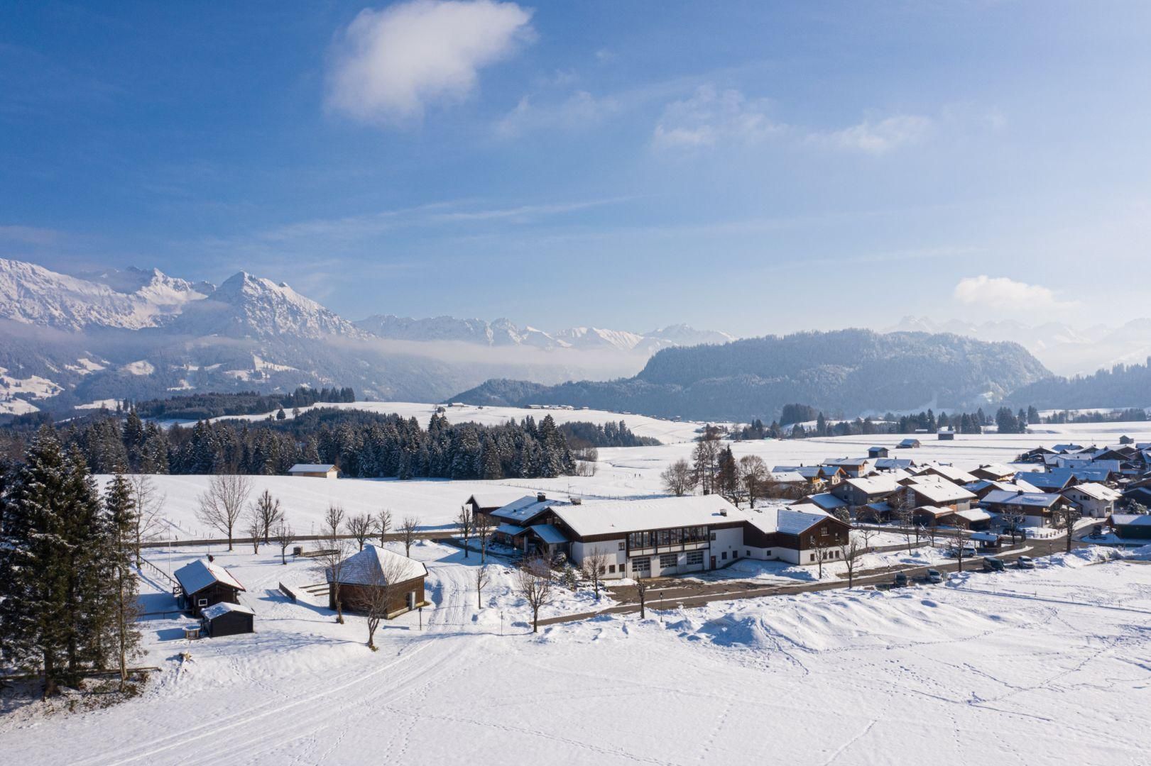 Winterliche Vogelperspektive auf einen verschneiten Parkplatz neben einem Gebäude.