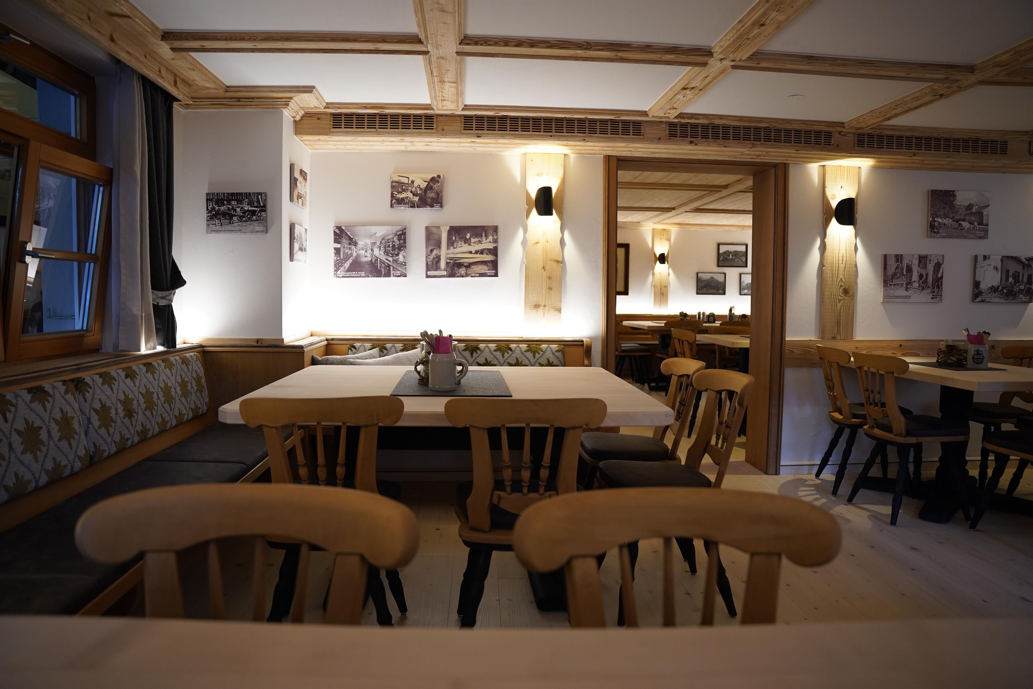 Ein gemütliches Restaurant mit Holzdekor und sanfter Beleuchtung. An den Wänden hängen historische Fotos, und die Tische sind mit Blumen geschmückt.