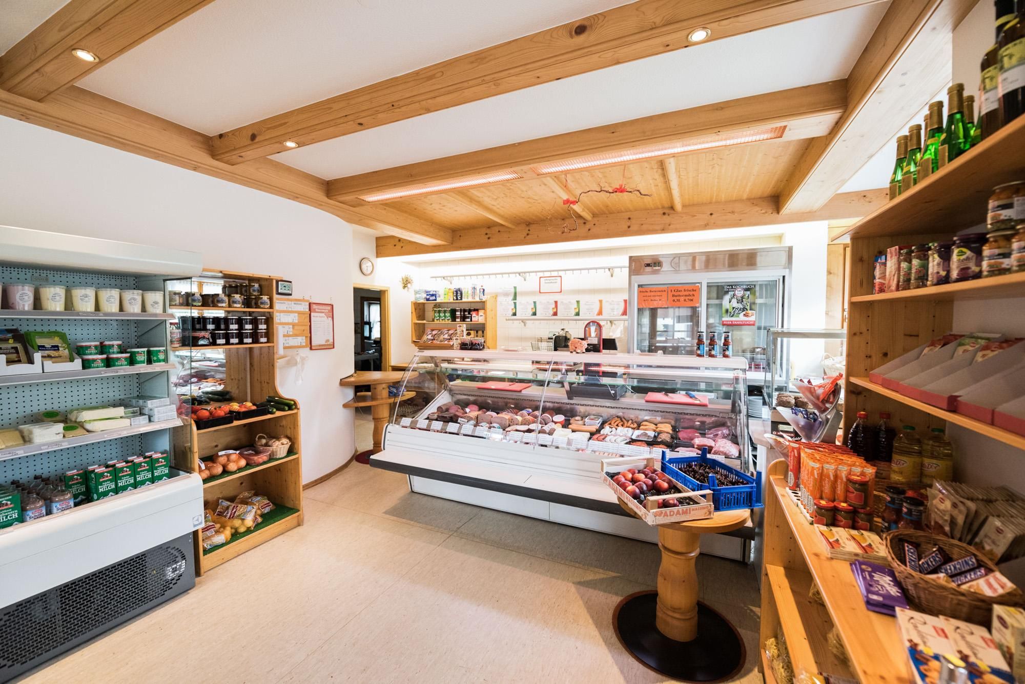Im Innenraum finden sich Regale, eine Kühltheke mit Fleisch und Käse sowie die Kasse.