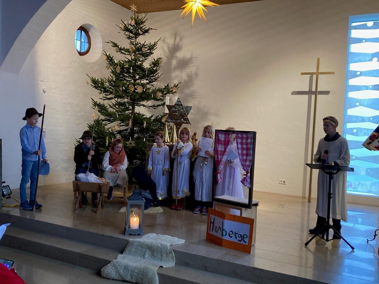 In der Evangelischen Kirche, ein Krippenspiel mit Kindern, im Hintergrund steht ein großer Weihnachtsbaum.