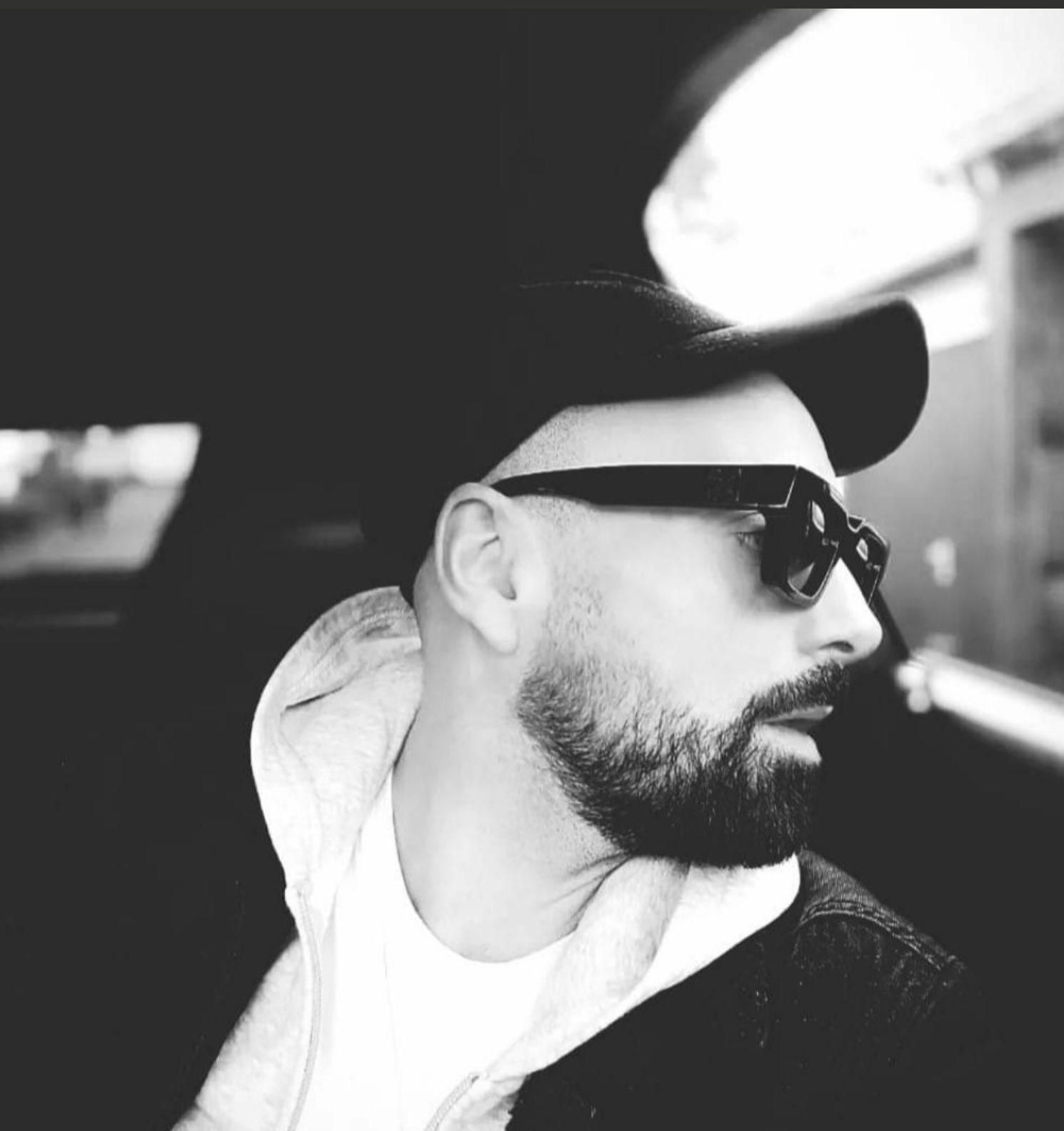 Ein schwarz-weiß Bild des Sängers Daniele Burgarella, mit schwarzem Vollbart und Sonnenbrille.