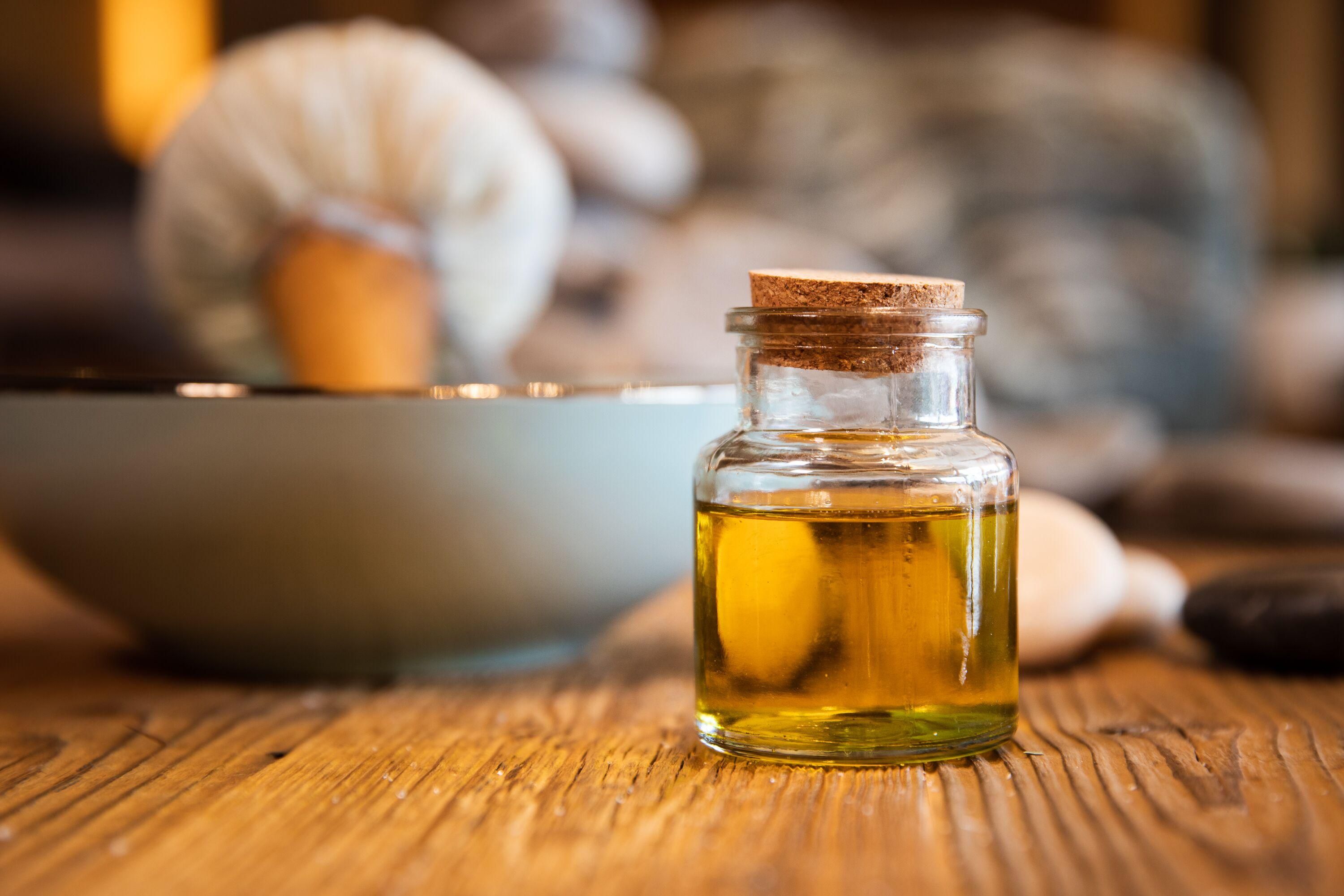 Ein kleinse Glasfläschchen mit gelber, öliger Flüssigkeit steht auf einem Holztisch.