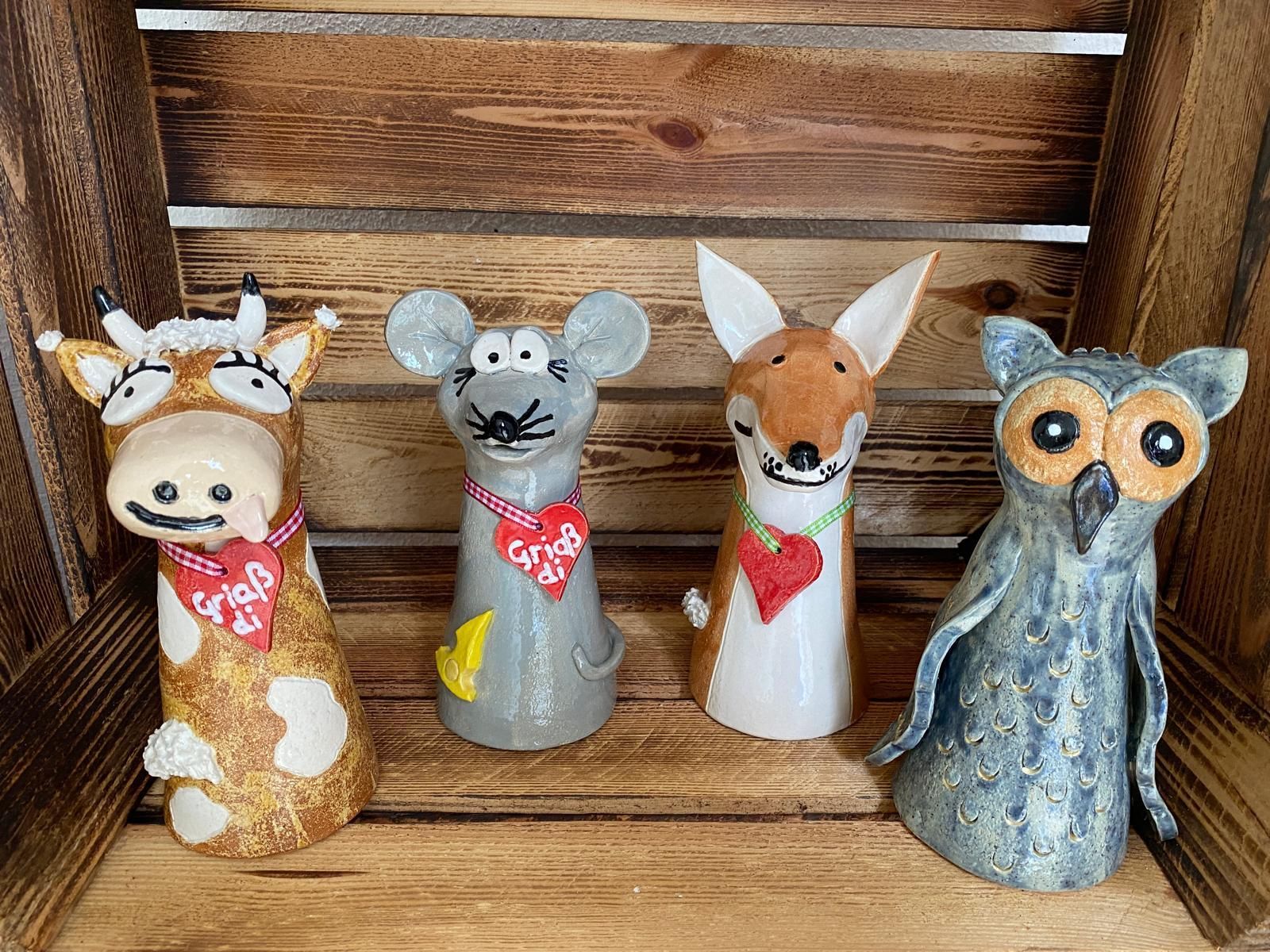 Nadjas Töpfer Krämle: Vier Keramikfiguren (Kuh, Maus, Fuchs, Eule) mit Herzen und Schriftzug "Griaß di" in Holzkiste.
