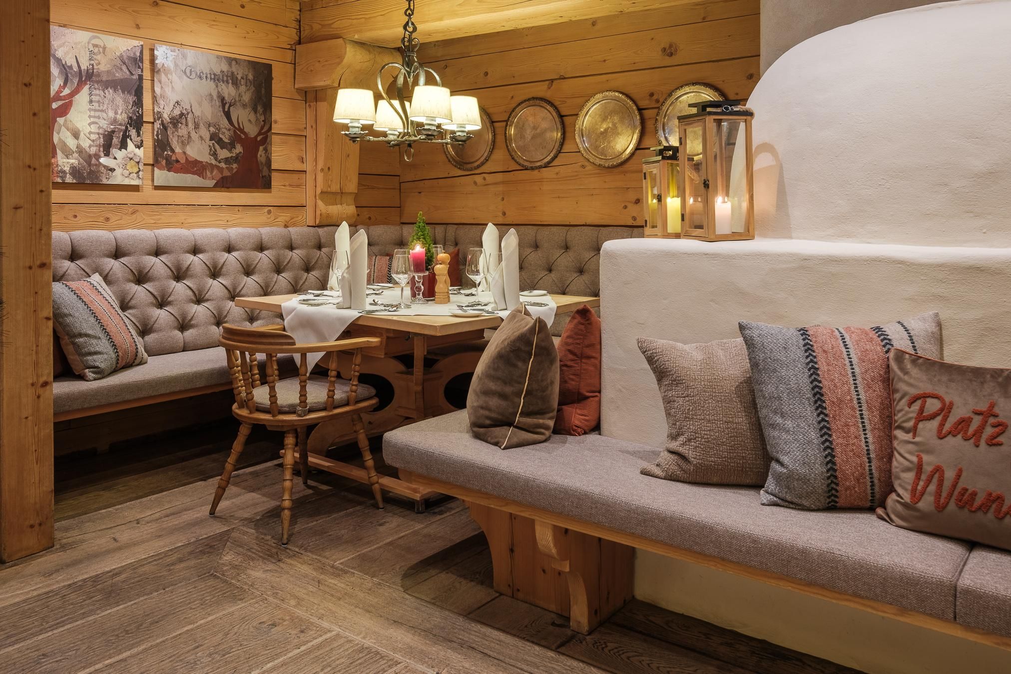 Ein gemütliches Restaurant mit Holzwänden und bequemen Sitzbänken. Die Einrichtung ist rustikal mit dekorativen Elementen und warmem Licht.