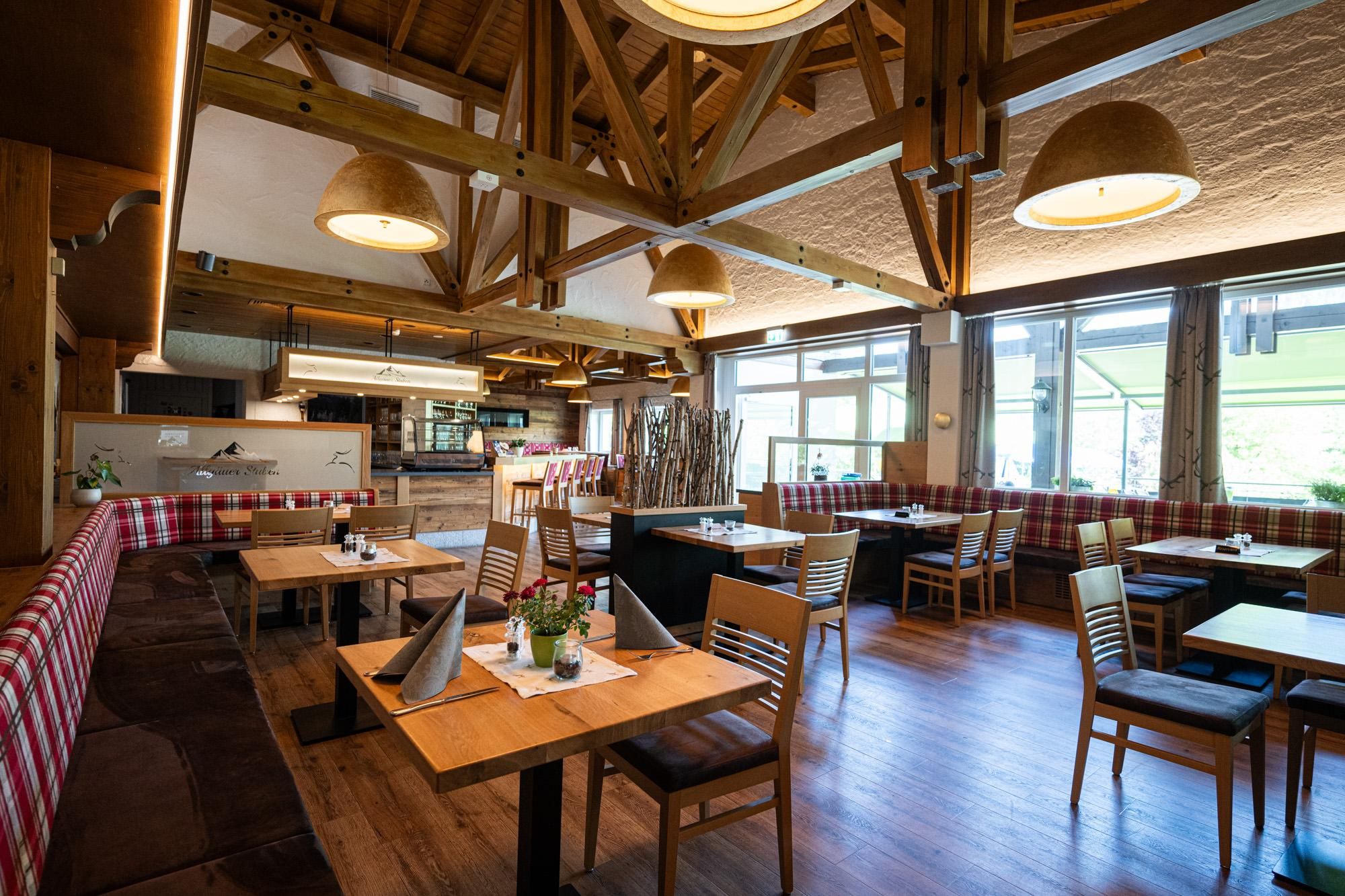 Restaurant Allgäuer Stuben innen: Holz, karierte Polster, gedeckte Tische, helle Lampen, Fenster. Gemütlich.