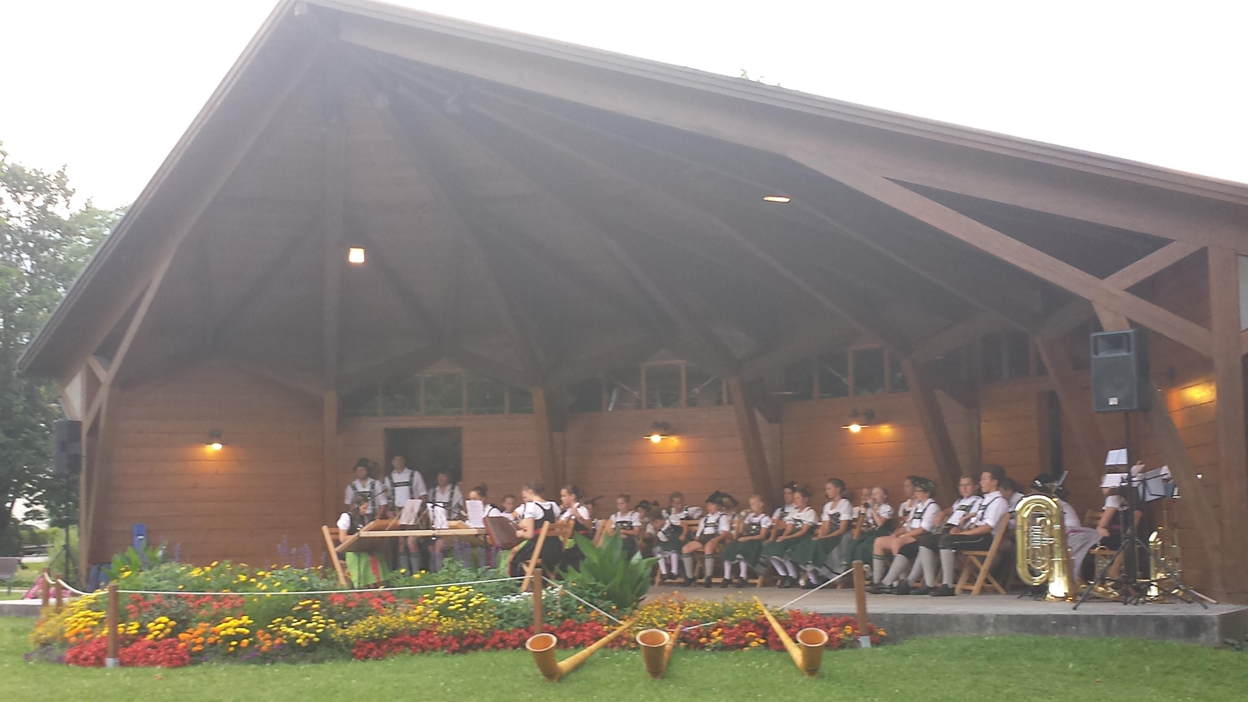 Musikpavillon vor dem Kurhaus Fiskina mit einer Musikkapelle, im Vordergrund drei Alphörner