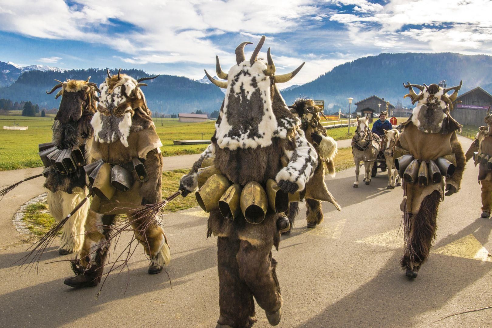 <p>Gruppe von fünf Klausen in Fellkostümen mit Hörnern und Glocken, die auf einer Straße gehen.</p>