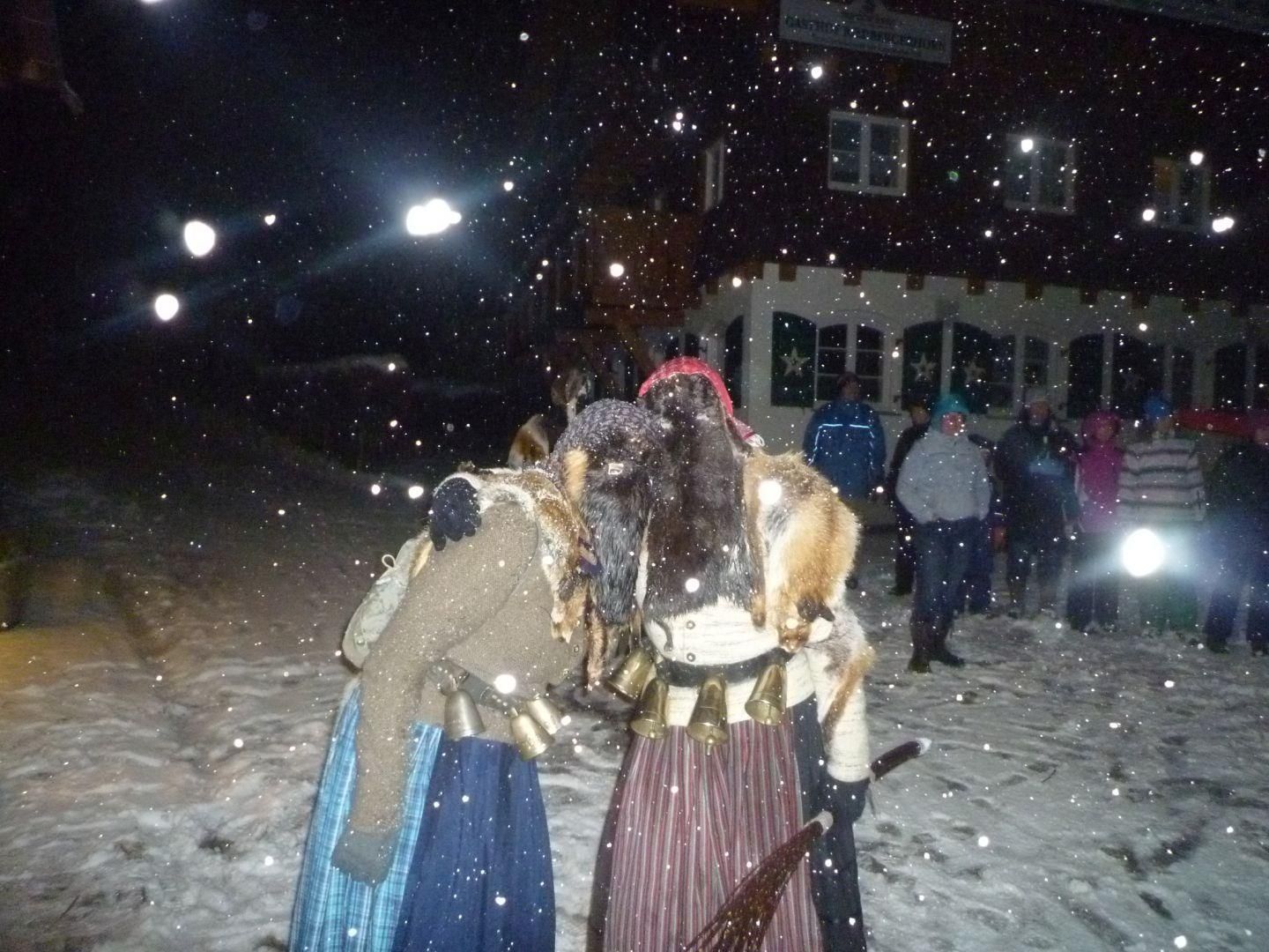 Zwei Bärbele beim Bärbeletreiben. Dumkle Umgebung und es schneit.