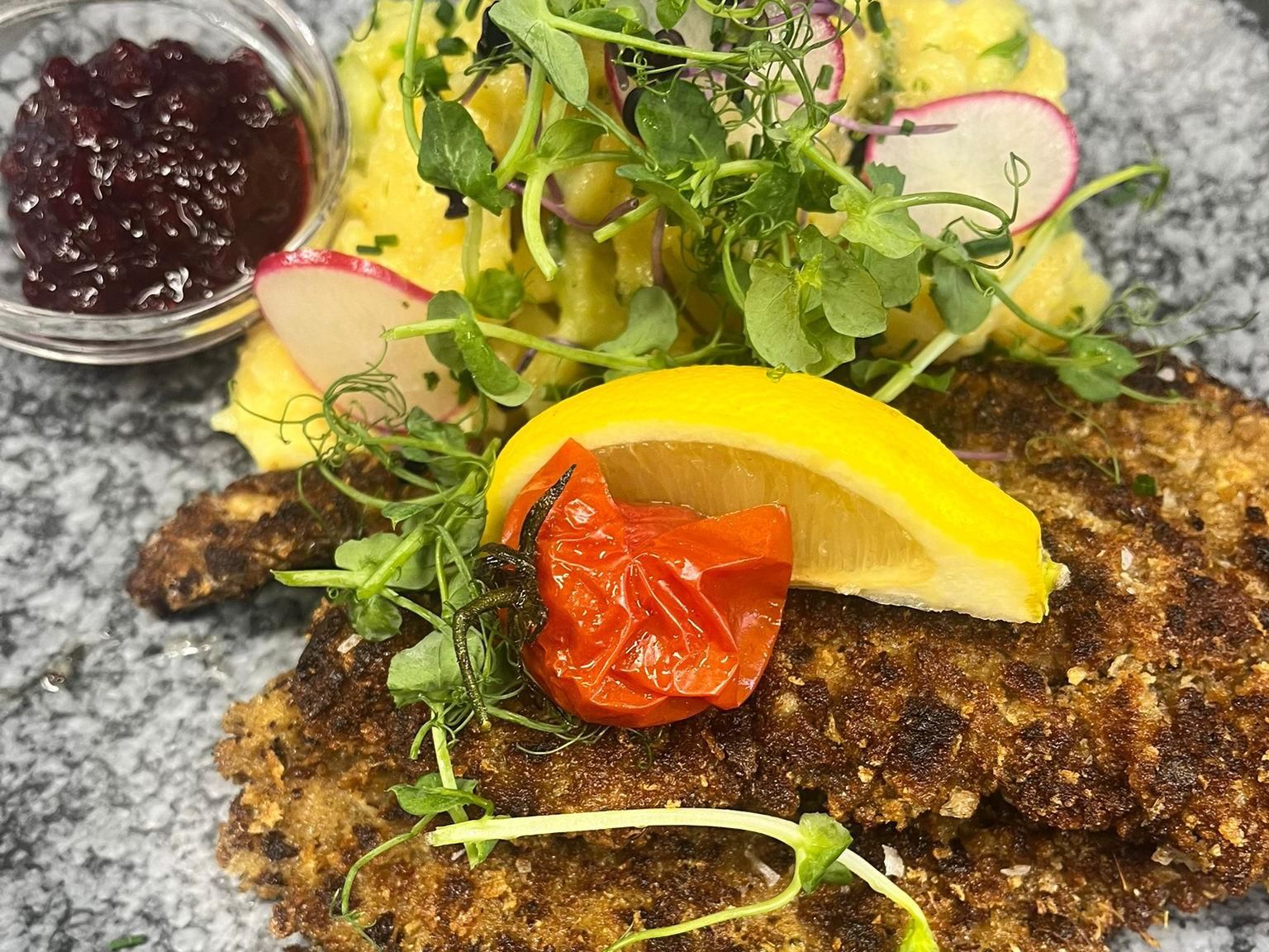Schnitzel mit Kartoffelsalat und Preiselbeeren, garniert mit Zitrone und Salat, vom Bauerngasthof Rothärmel's beim Mayr in Ofterschwang.