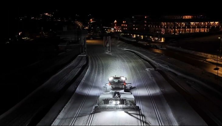 Ein Pistenfahrzeug präpariert nachts eine schneebedeckte Loipe