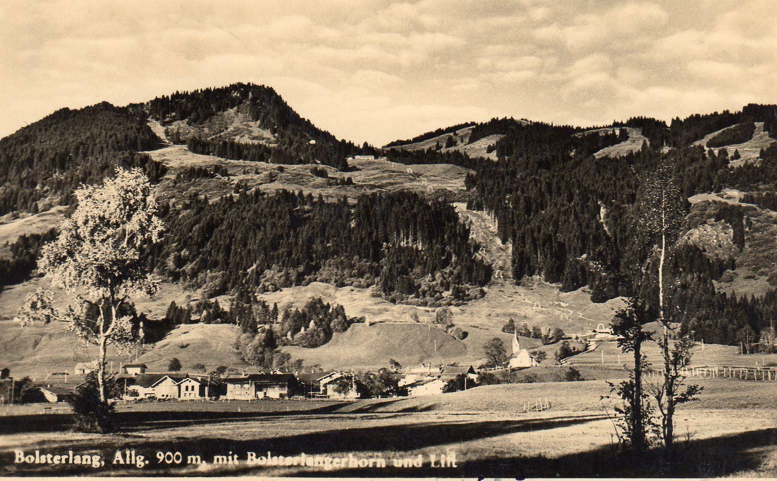 Sepia Aufnahme eines Ortes mit alten Bauernhäusern und einer Kapelle auf einem Plateau. Im Hintergrund ein Berg mit viel Wald und alten Stützen einer Bahn.
Schriftzug unten links: Bolsterlang, Allg. 900 m. mit Bolsterlangerhorn und Lift