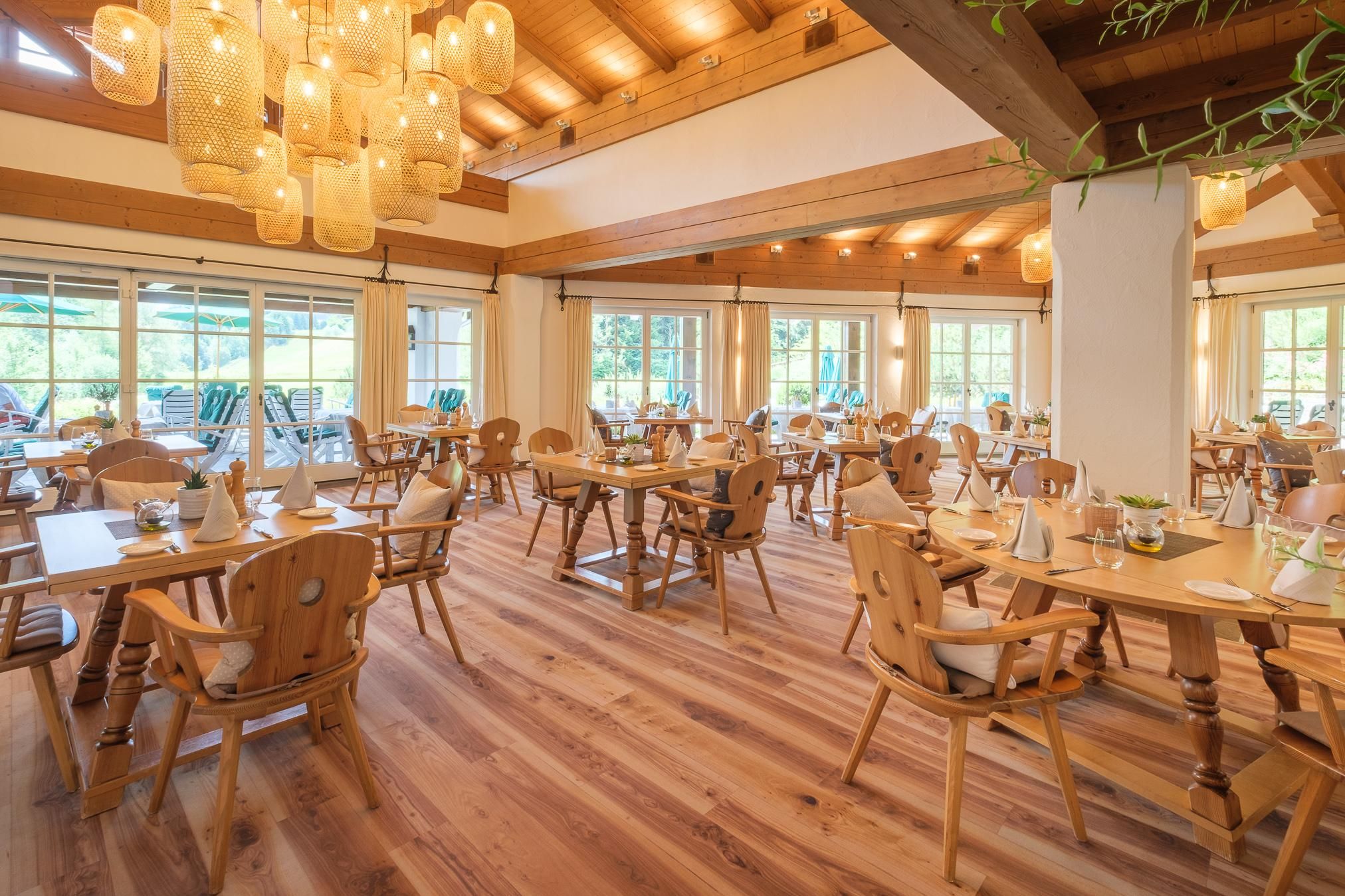 Heller und freundlicher Innenraum des Restaurant Seehaus - La Cucina Inizio. Holzböden und -decken mit sichtbaren Balken. Helle Holztische und Stühle mit weißen Kissen. Große Fensterfront.
